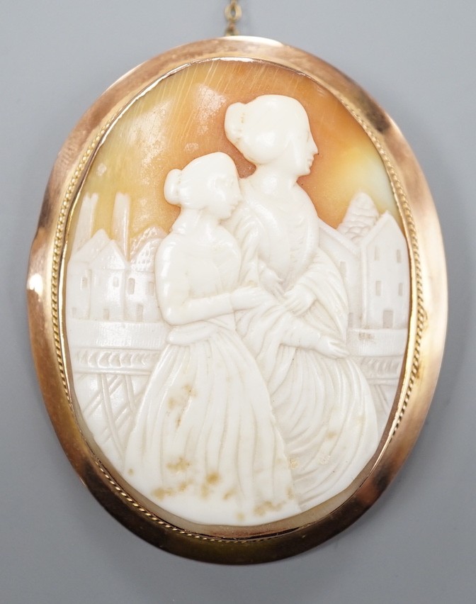 A 9ct mounted oval cameo shell brooch, carved with two ladies in a townscape, 58mm, gross weight 17.8 grams.